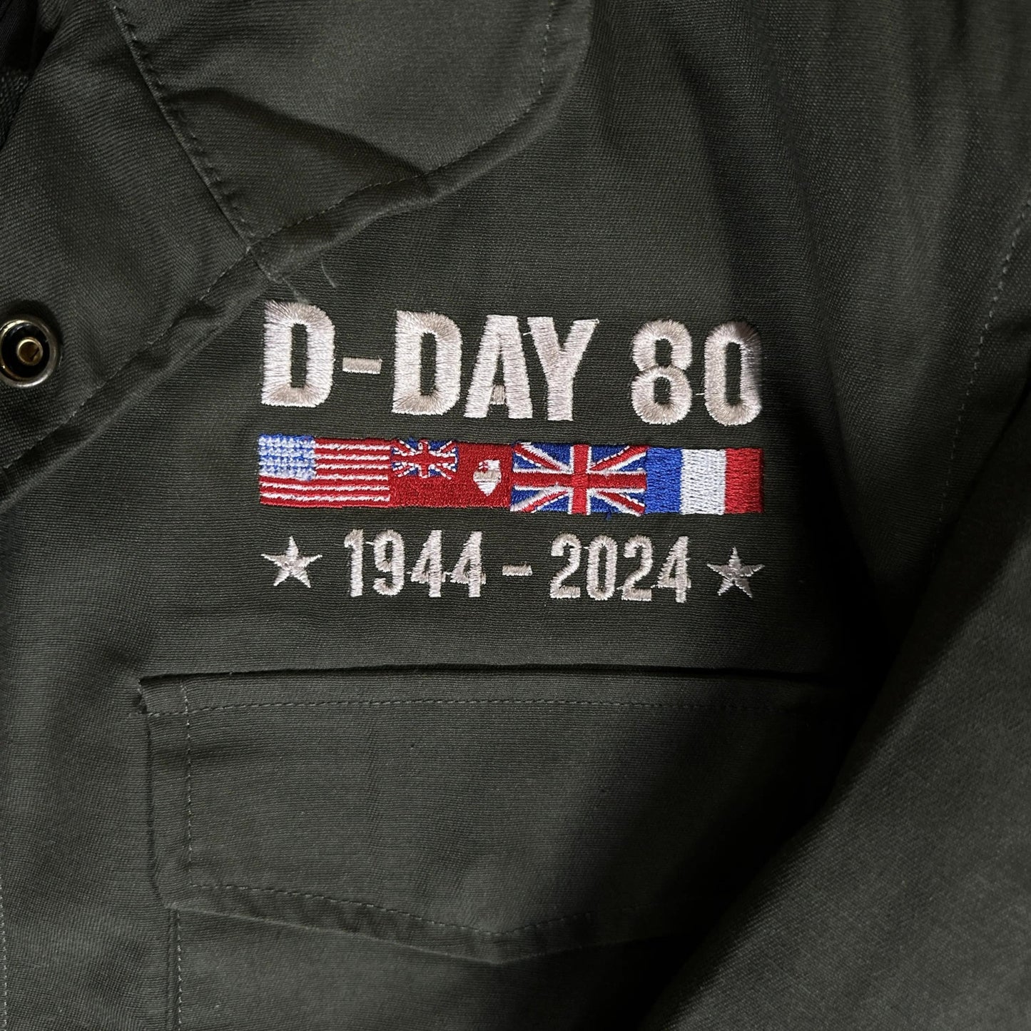 Close-up detail of the M65 Army field coats with original D-Day 80th Anniversary design and a 48-star flag from The History List Store.