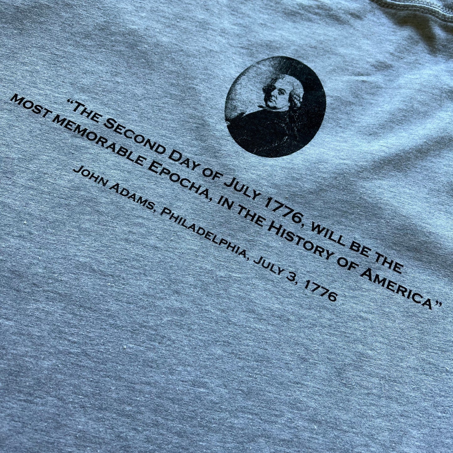 Close-up of the back of "Happy July 2” v-neck shirt with John Adams and his quote on the back from The History List store in heather grey color
