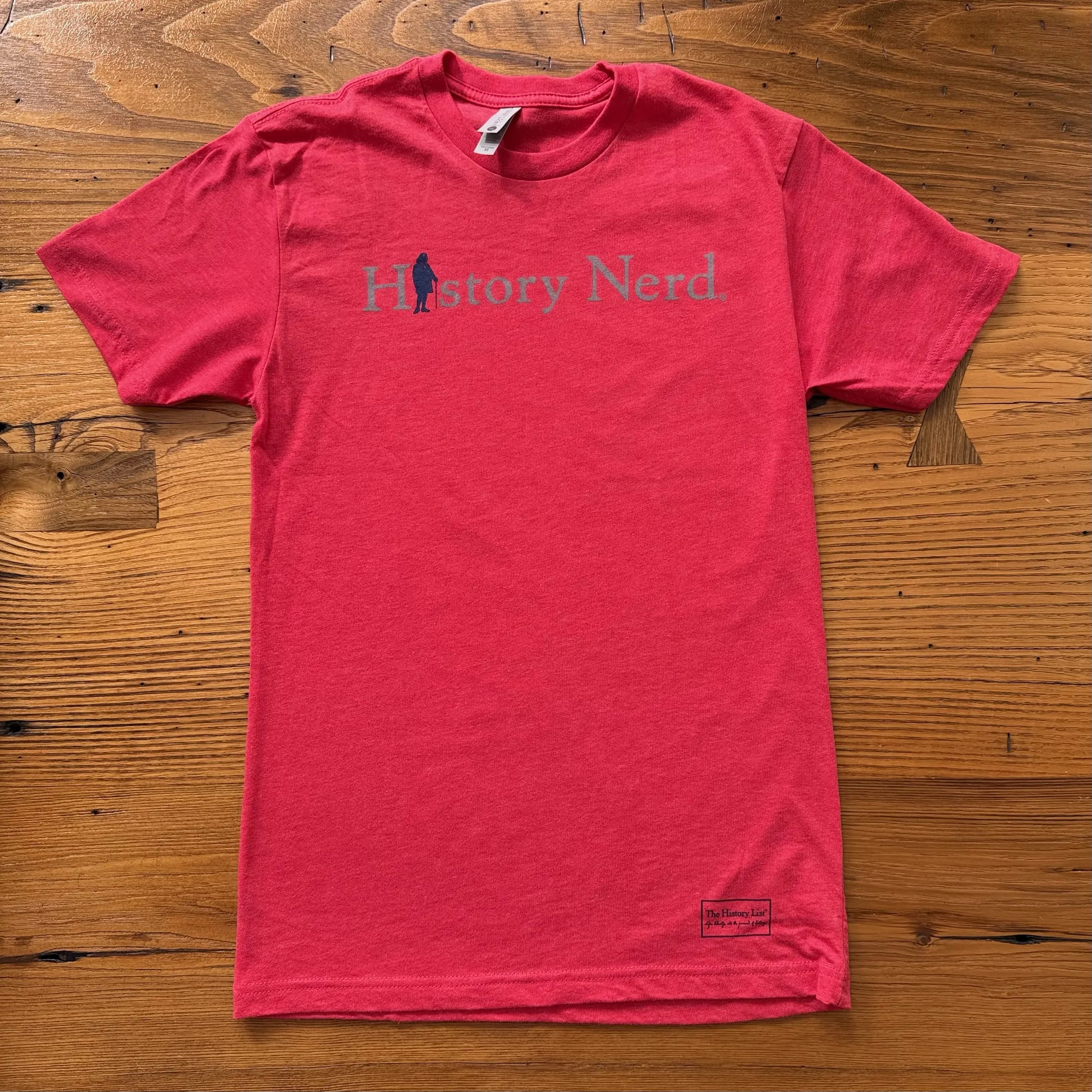Red t-shirt with 'History Nerd' text on a wooden surface from The History List store