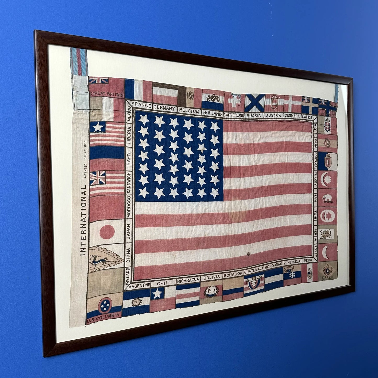 Printed for the 1875 Centennial Exhibition: US flag surrounded with the flags of participating nations — Framed